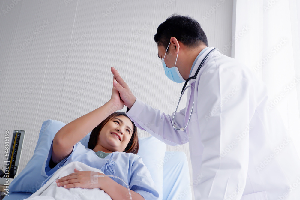 Obraz premium The doctor encouraged Ready to touch the hand of a female patient who is giving saline solution on the patient's bed.