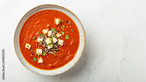 Round bowl with garnished pureed tomato soup, light background, copy space 