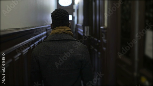 Young black man walking through corridor leaving house, person getting out