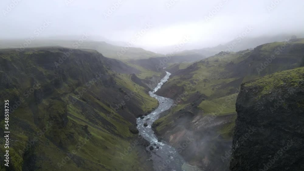 Aerial push in shot of a river in the mountain gorge of Fossárdalur, in Iceland, on a cloudy and foggy day Aerial push in shot of a river in the mountain gorge of Fossárdalur, in Iceland, on a cloudy and foggy day