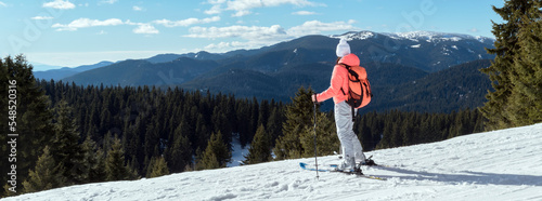 Panoramic view woman skier with backpack and winter mountains nature background. Young girl ski tourist enjoy view of snowy mountain valley during ski trip. Ski resort Pamporovo, Bulgaria photo