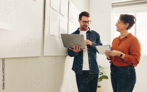 Two happy business colleagues having a discussion in an office