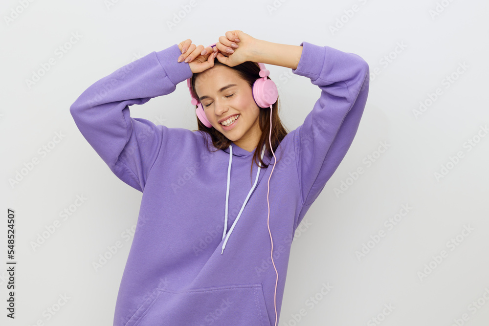 a surprised, emotional woman stands on a white background with her hands near her face and looks at the camera with her mouth wide open, listening to music in pink headphones a surprised, emotional woman stands on a white background with her hands near her face and looks at the camera with her mouth wide open, listening to music in pink headphones
