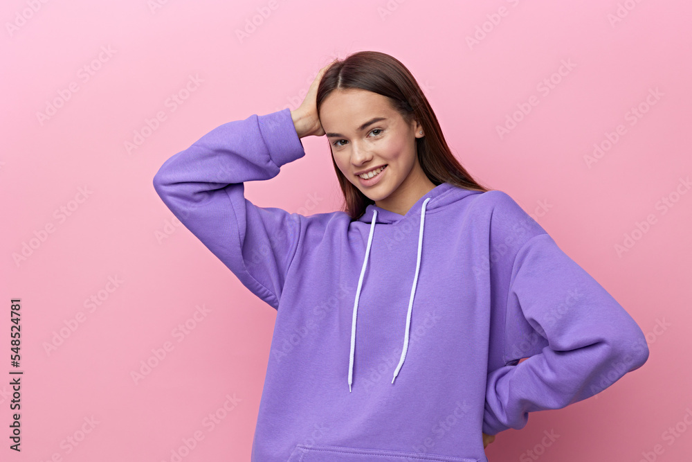 an enthusiastic woman stands looking forward on a pink background in a purple suit, smiling cheerfully, put her hand on her head, lowering the second one down an enthusiastic woman stands looking forward on a pink background in a purple suit, smiling cheerfully, put her hand on her head, lowering the second one down