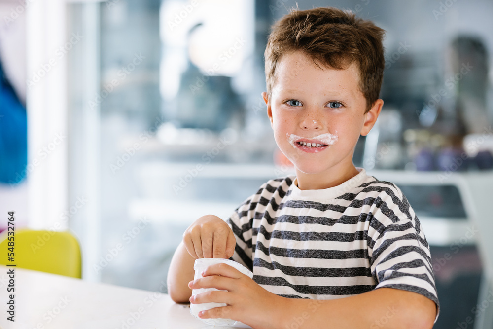 Cheerful boy smeared with yogurt around mouth Cheerful boy smeared with yogurt around mouth