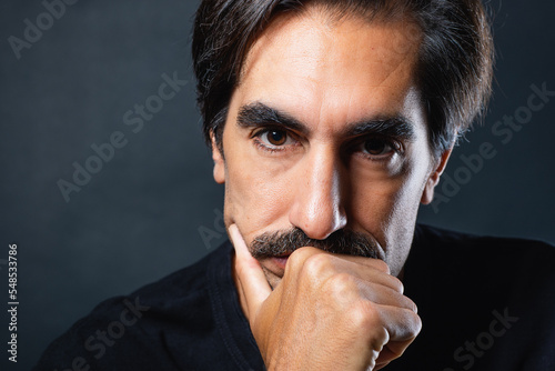 Serious man with mustache on black background photo