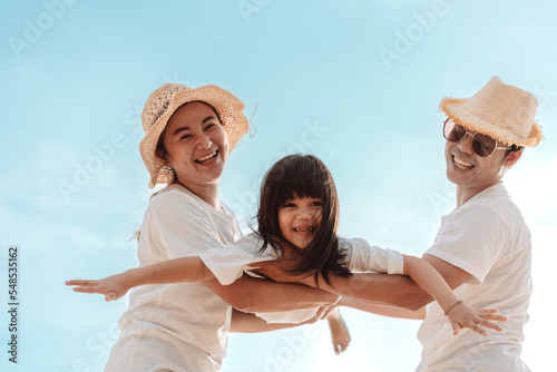 Happy asian family enjoy the sea beach at consisting father, mother and daughter having fun playing beach in summer vacation on the ocean beach. Happy family with vacations time lifestyle concept.
