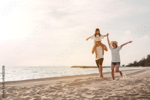 Happy asian family enjoy the sea beach at consisting father, mother and daughter having fun playing beach in summer vacation on the ocean beach. Happy family with vacations time lifestyle concept.