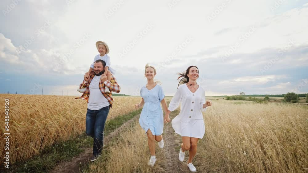 Happy family runs in wheat field and laughs. Dad holds little son on shoulders, mom and teenage daughter hold hands. Adventure and outdoors rest. Active sports lifestyle. Enjoyment together leisure. Happy family runs in wheat field and laughs. Dad holds little son on shoulders, mom and teenage daughter hold hands. Adventure and outdoors rest. Active sports lifestyle. Enjoyment together leisure.