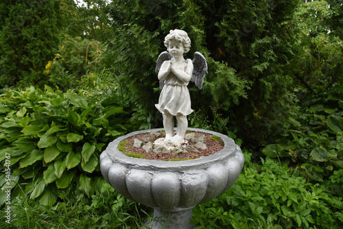 A wet statue of a little angel in the garden of a convent in the Russian city of Volkhov.