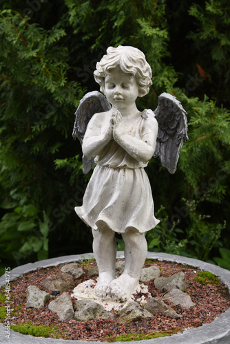 A wet statue of a little angel in the garden of a convent in the Russian city of Volkhov.