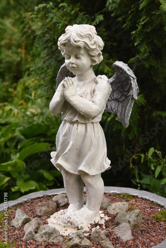 A wet statue of a little angel in the garden of a convent in the Russian city of Volkhov.