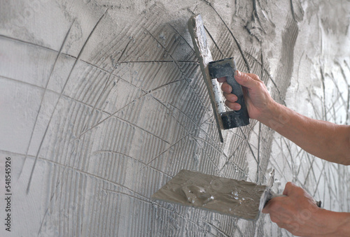 worker hands plaster over scratched new wall. plastering with scratch marks on first layers wall surface to helps second coat of plaster to adhere scratch coat create a bond between the two layers photo