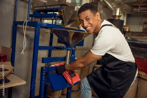 Cheerful worker sealing a coffee bag with the heat sealer