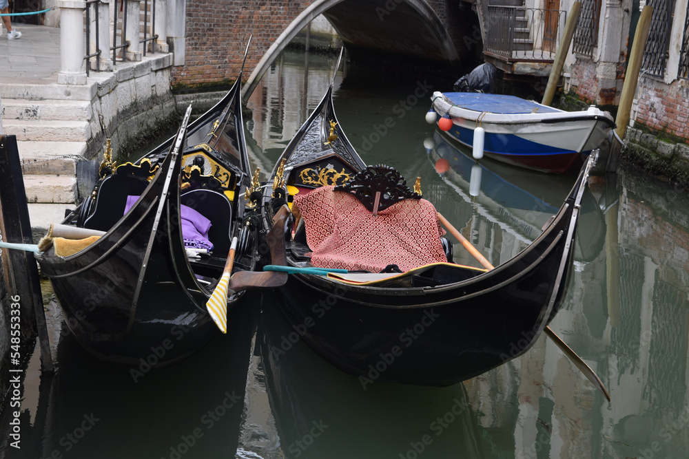 close-up of two docked Gondolas on a canal in Venice near a bridge