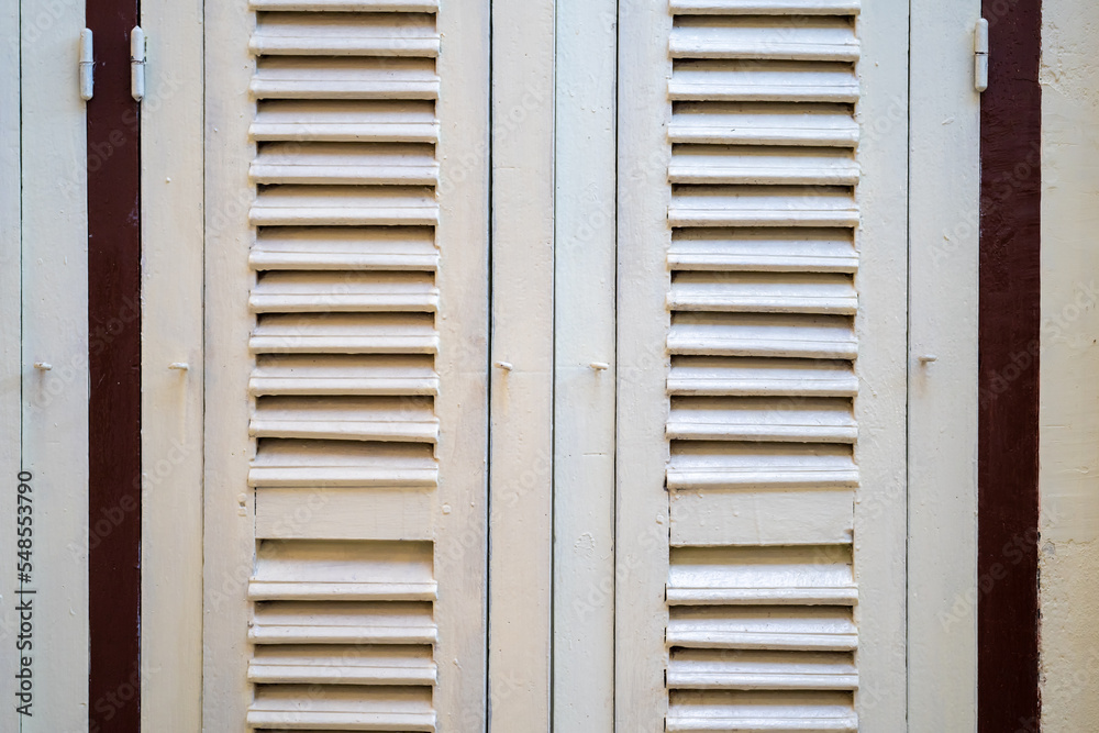 Fototapeta premium Closing white wooden vintage door in Thailand with cement white creamy colour wall beside it.