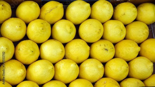 rows of  ripe yellow lemons in a box at the market