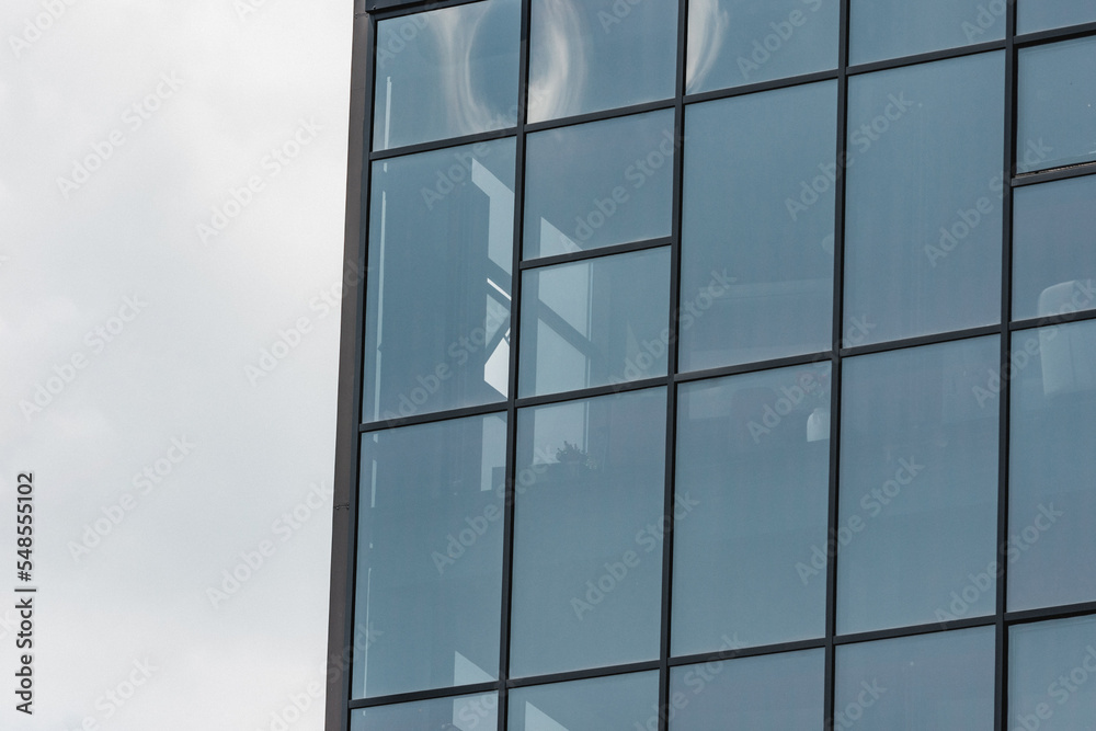 Modern business office exterior full of windows. Front side of a tall commercial building or work place