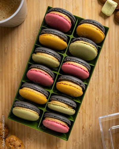 Vertical top view of colorful French macarons in a box over the wooden surface