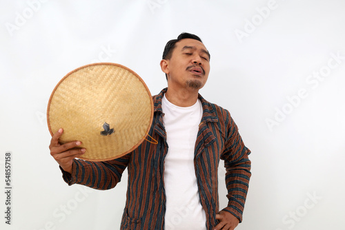 Relaxed asian farmer standing while carrying hat. Isolated on white background photo