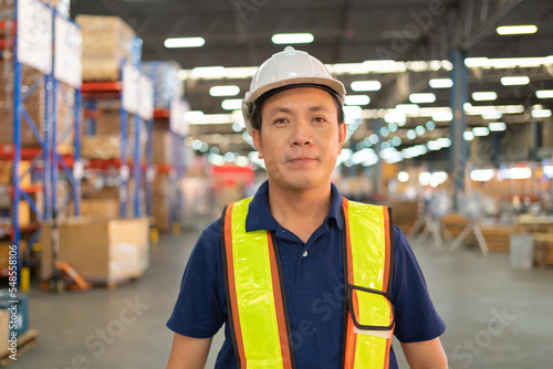 Portrait of Asian worker working in large warehouse retail store industry. Rack of stock storage. Interior of cargo in ecommerce and logistic concept. Depot. People lifestyle. Shipment service.