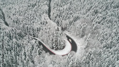 Drone footage. Winter landscape. Mountain road in snow-covered dense forest. photo