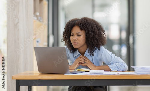 Portrait of tired young business african american woman work with documents tax laptop computer in office. Sad, unhappy, Worried, Depression, or employee life stress concept