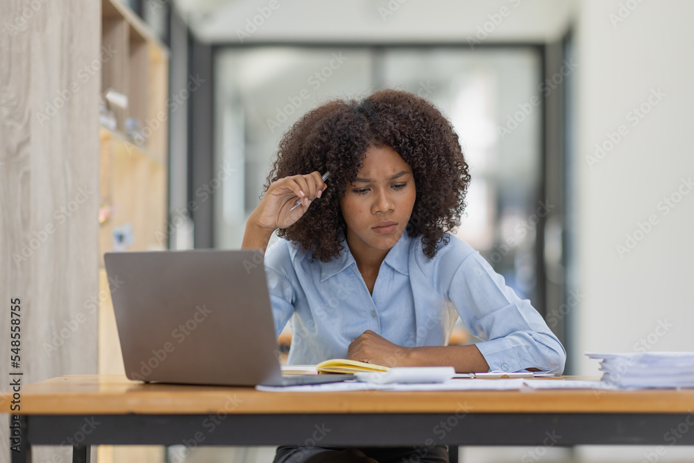Portrait of tired young business african american woman work with documents tax laptop computer in office. Sad, unhappy, Worried, Depression, or employee life stress concept Portrait of tired young business african american woman work with documents tax laptop computer in office. Sad, unhappy, Worried, Depression, or employee life stress concept