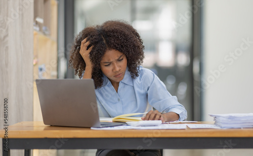 Portrait of tired young business african american woman work with documents tax laptop computer in office. Sad, unhappy, Worried, Depression, or employee life stress concept