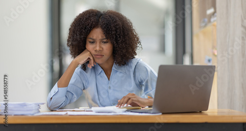 Portrait of tired young business african american woman work with documents tax laptop computer in office. Sad, unhappy, Worried, Depression, or employee life stress concept