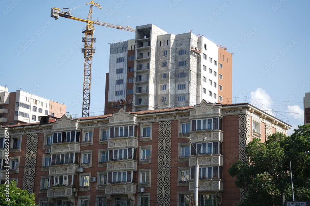Fototapeta premium Almaty, Kazakhstan - 04.26.2022 : A residential building with an old design and a new residential complex under construction