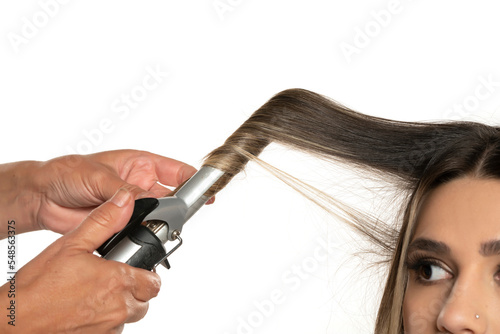 Stylist using curling iron for hair curls, close-up, isolated on white background