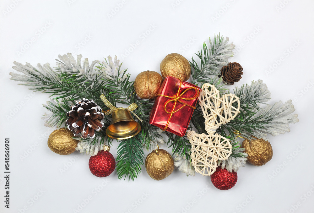 Festive border from pine tree branches ,decorative balls, cones, nuts, bell, gift and rattan hearts on white background. Top view, flat lay. Christmas greeting concept. Free space for message Festive border from pine tree branches ,decorative balls, cones, nuts, bell, gift and rattan hearts on white background. Top view, flat lay. Christmas greeting concept. Free space for message