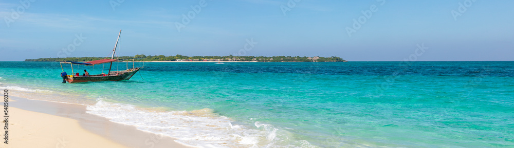 Sandbank in der Menai-Bay auf der Insel Sansibar, Dhow am Strand im türkisblaues Wasser und blauer Himmel am schönen Sandstrand in Tansania als Panorama.