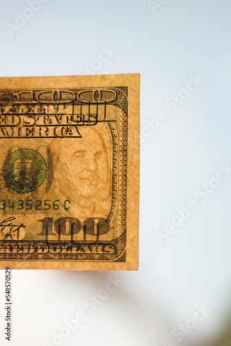 Hundred dollar bill in bright sunlight. Close-up with a blurred background.