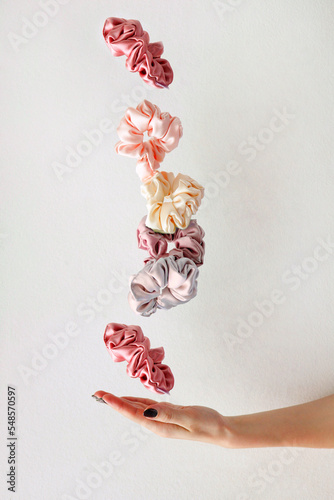 levitation of Colorful silk Scrunchies on woman hand isolated white. Hair tools and accessories.