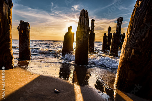 Zachód słońca nad morzem Bałtyckim z falami uderzającymi o falochrony