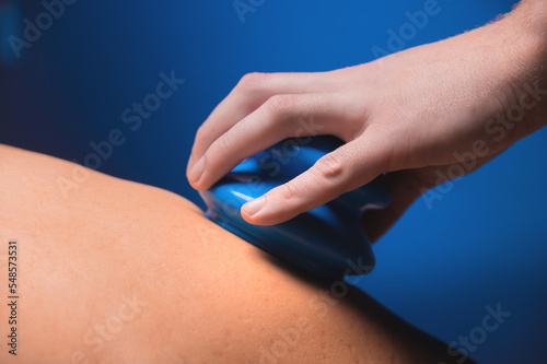 hand places a blue rubber massage jar on a man's back. Close-up