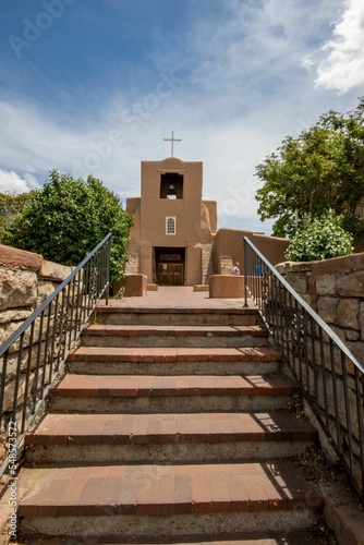 San Miguel Chapel in Santa Fe, New Mexico with brown steps leading to it under a sunny blue sky photo