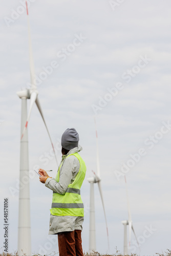 female engineer in a protective vest takes measurements of the speed of wind turbines. electricity is generated by wind. technologies without an eco trace. engineering solution. generating electricity
