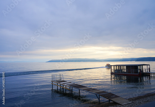 wooden bridge into the water against the backdrop of mountains and sea boat
