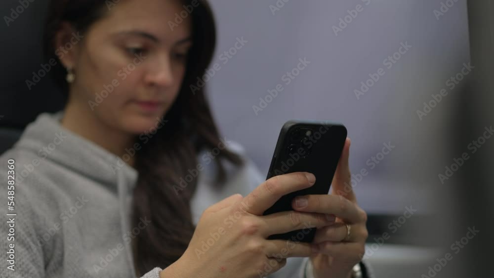 Woman texting message while traveling by train. Passenger commuting to work or study using modern technology. Person typing on smartphone device Woman texting message while traveling by train. Passenger commuting to work or study using modern technology. Person typing on smartphone device