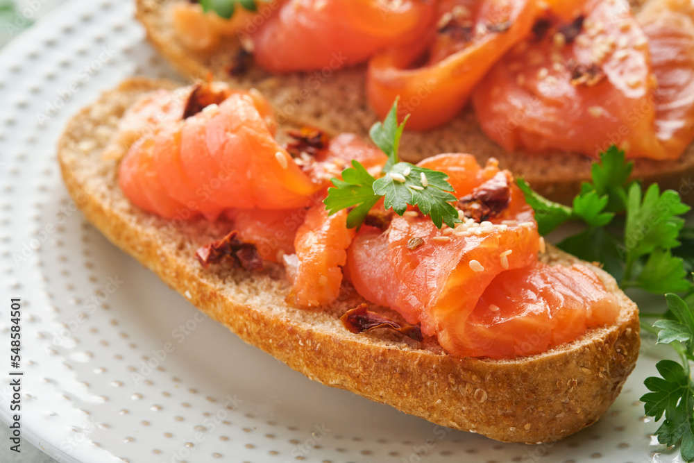 Sandwiches with salted salmon. Open sandwiches from cereal or whole grain rye bread with salted salmon, sesame seeds and dried tomato on white marble stand. Seafood. Healthy food. Scandinavian cuisine Sandwiches with salted salmon. Open sandwiches from cereal or whole grain rye bread with salted salmon, sesame seeds and dried tomato on white marble stand. Seafood. Healthy food. Scandinavian cuisine