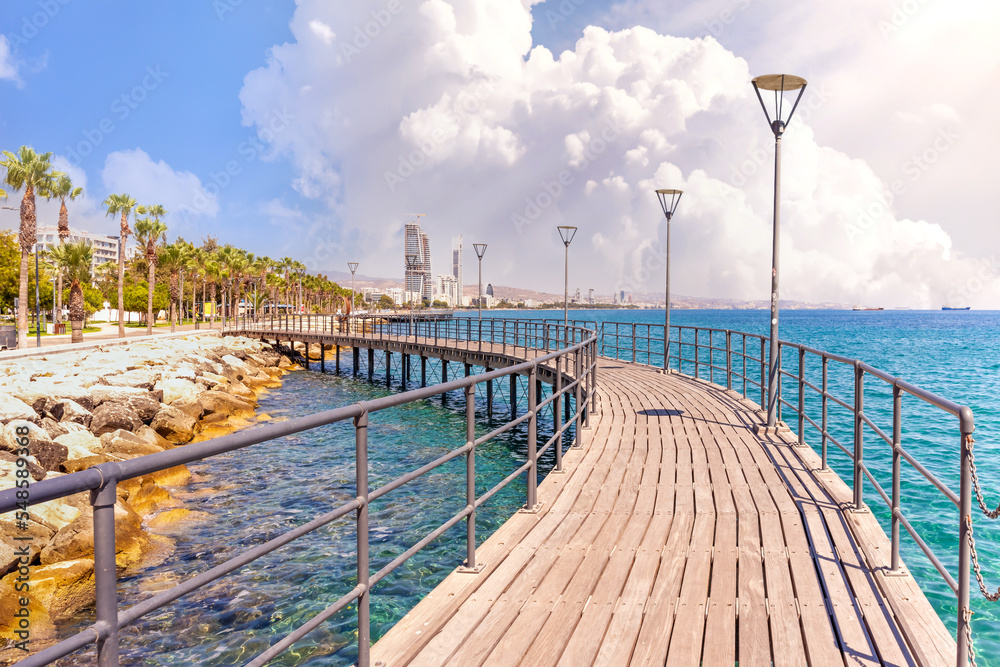 Molos Promenade in Limassol city in Cyprus . View of landmark with palm trees, pools of water, the Mediterranean sea and people walking.