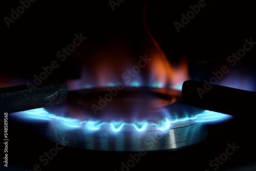 Gas hob. Hob is lit showing blue flames. Exposed to show the gas flames blue and orange. Inefficient burning concept and fossil fuel usage.  