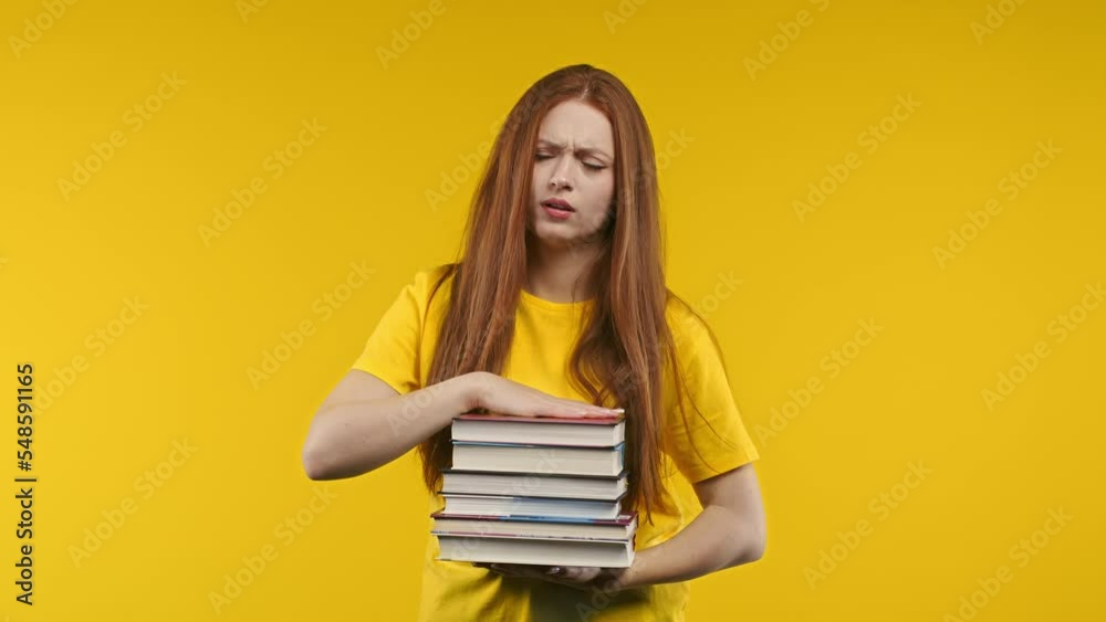 Lazy woman student is dissatisfied with amount of books homework on yellow background. Girl with long hair in displeasure, she is annoyed, discouraged frustrated by studies Lazy woman student is dissatisfied with amount of books homework on yellow background. Girl with long hair in displeasure, she is annoyed, discouraged frustrated by studies