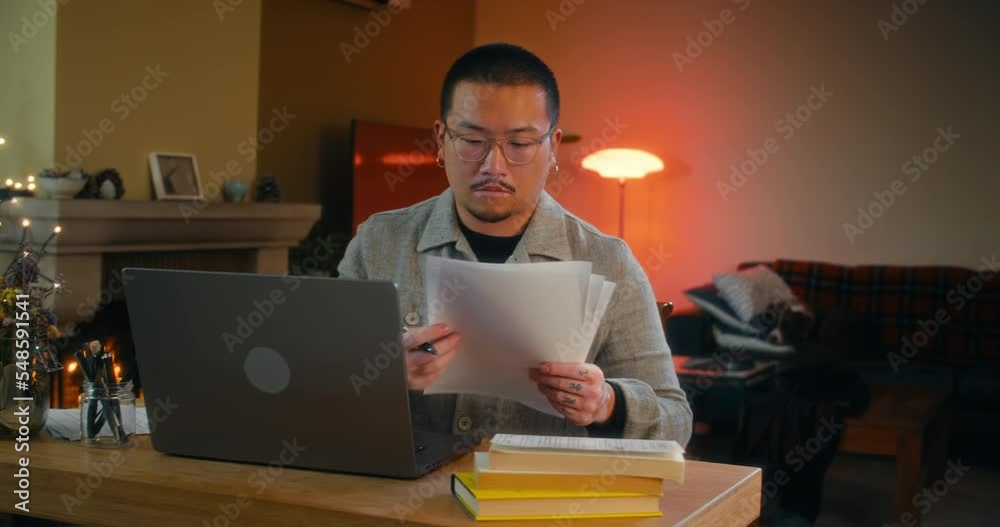 Freelance Chinese guy work in home at night in living room with fireplace Freelance Chinese guy work in home at night in living room with fireplace