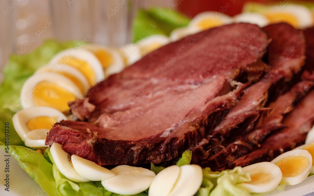 Slices of smoked roasted holiday ham meat served on salad plate with boiled eggs, traditional Easter dish, festive dinner