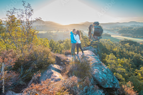  Ein Paar genießt nach der Wanderung, vom Gipfel des Berges, die atemberaubende Aussicht der Landschaft mit einem wunderschönen Sonnenuntergang