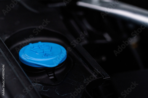 Closeup blue windshield washer fluid reservoir cap in engine room. Liquid caps inside a car engine. Windshield washer fluid reservoir cap.